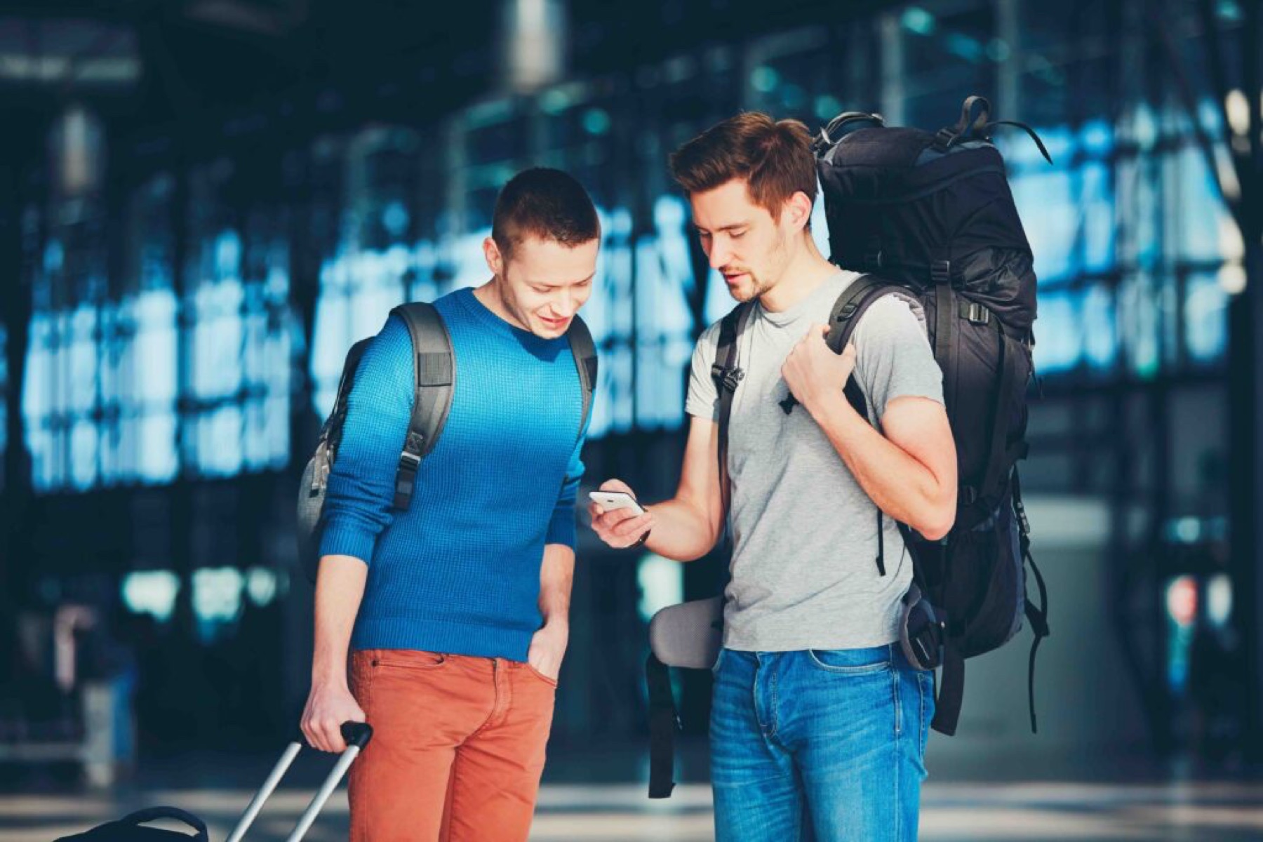 Two travellers looking at a phone in an airport